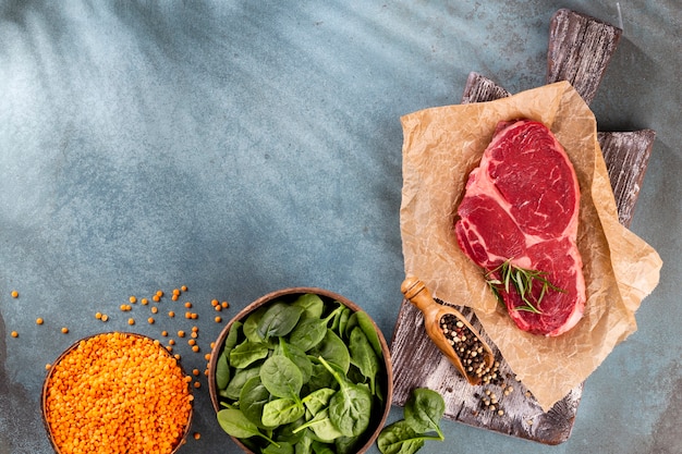 Foto verse rauwe ribeye steak op houten snijplank met spinazie linzen en rozemarijn