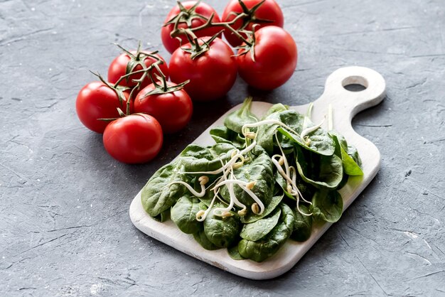 Verse rauwe spinazie op een houten bord Rauwe verse rode tomaten Gezonde voeding Dieetvoeding