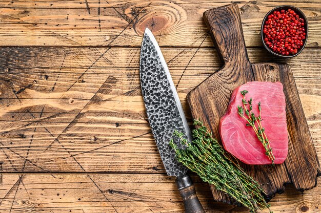 Verse rauwe tonijnsteak op een houten snijplank met mes