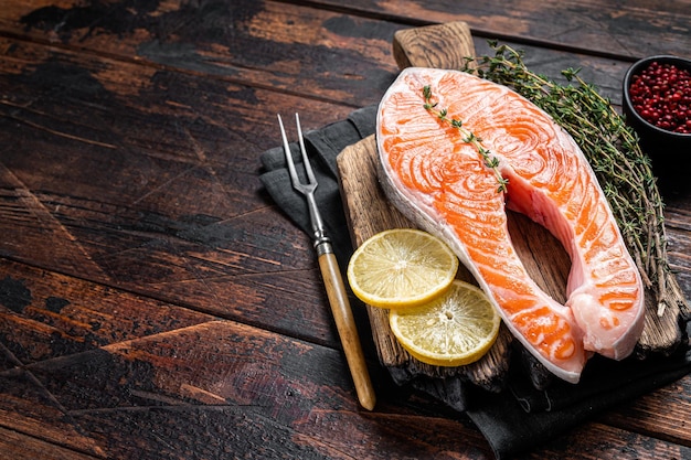 Verse rauwe zalm forel vis steaks op een houten bord met tijm en citroen. Houten achtergrond. Bovenaanzicht. Ruimte kopiëren.