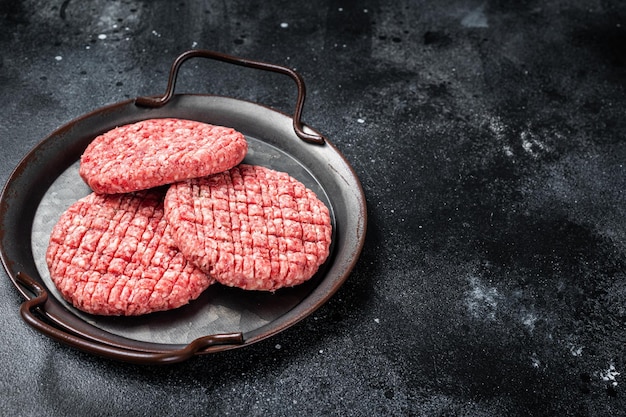 Verse rauwe zelfgemaakte rundergehakt hamburger in stalen dienblad Zwarte achtergrond Bovenaanzicht Kopieer ruimte