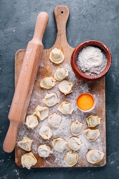 Verse rauwe zelfgemaakte tortellini of ravioli pasta op donkere achtergrond