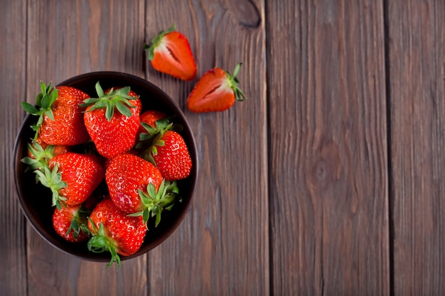 Verse rijpe aardbeien in een bruine kom op een bruin houten achtergrond