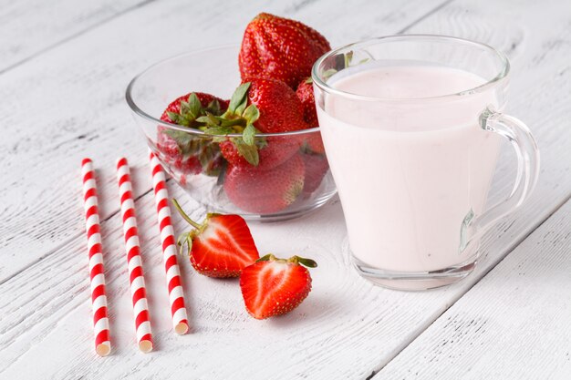 Verse rijpe aardbeien met melk in glas