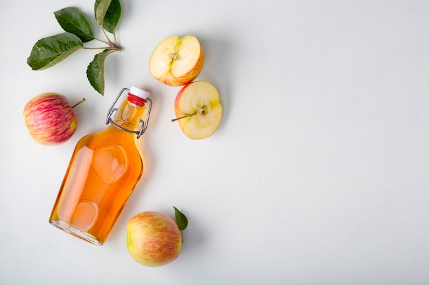 Verse rijpe appels en appelciderazijn. Appelcider in een glazen fles en verse appels. Lichte achtergrond. Bovenaanzicht. Kopieer de ruimte van uw tekst.