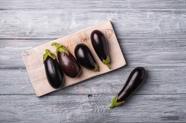 Verse rijpe aubergine op houten snijplank, grijze houten achtergrond, bovenaanzicht