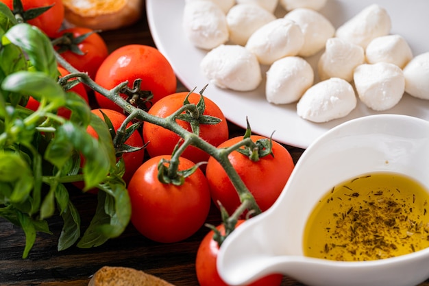 Verse rijpe basilicumblaadjes met aromatische tomaten en italiaanse mozzarella, op tafel. naast bruschetta en olijfolie met Provençaalse kruiden