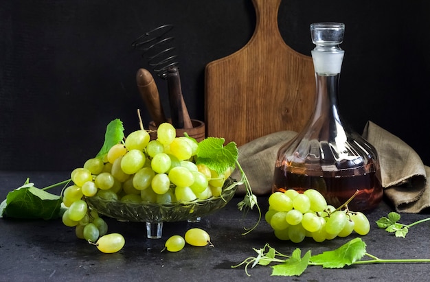 Foto verse rijpe druiven in een fruitschaal en karaf met druivensap. keukengerei op achtergrond