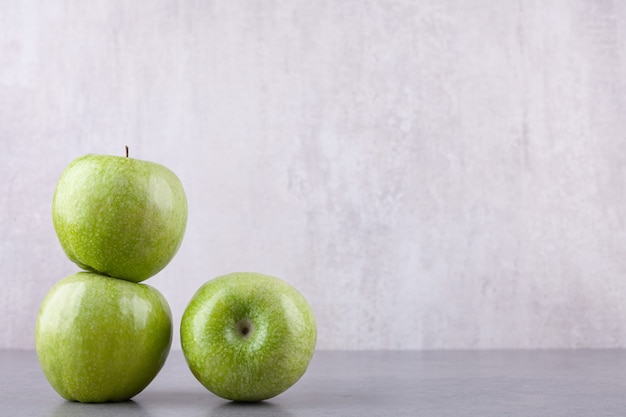 Verse rijpe groene appels geplaatst op een stenen achtergrond.