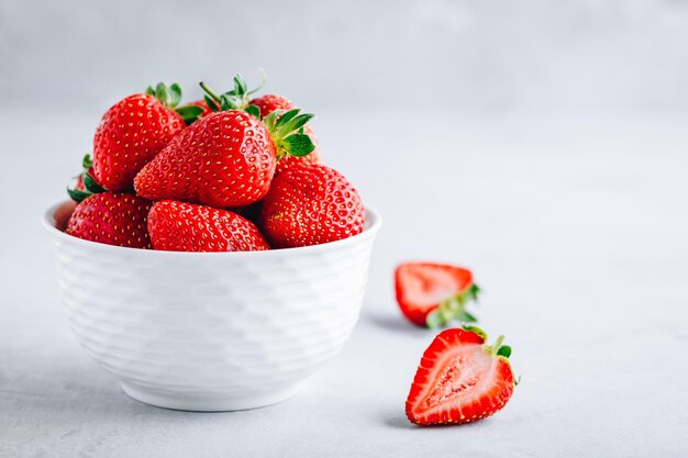 Verse rijpe heerlijke aardbeien in een witte kom op een grijze steenachtergrond