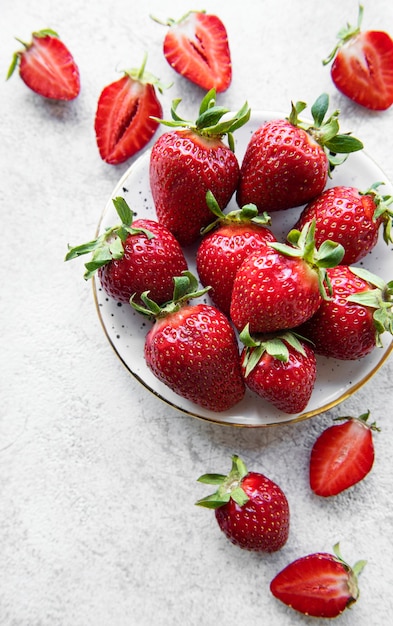 Verse rijpe heerlijke aardbeien in een witte plaat op een grijze steenachtergrond