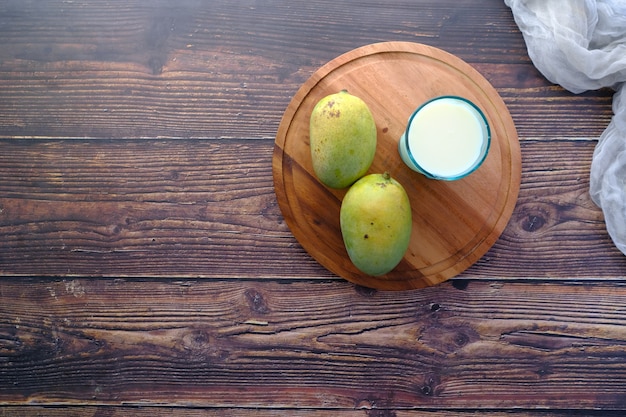 Verse rijpe mango en glas melk op tafel