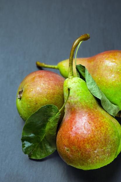 Verse rijpe peren op zwarte schalie staan.