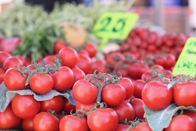 Verse rijpe sappige tomaten op de markt met prijskaartjes die groentenconcept verkopen