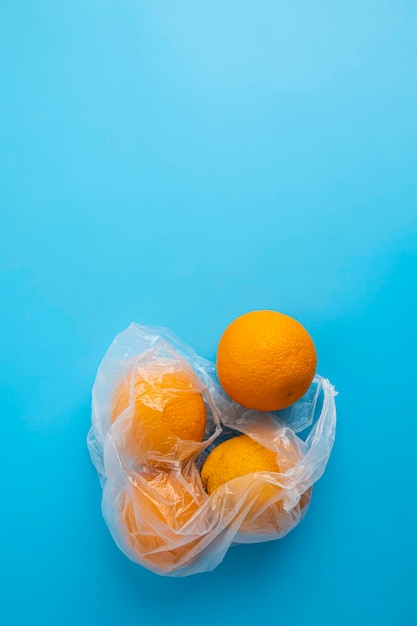 Verse rijpe sinaasappelen in een doorzichtige plastic zak op een blauwe achtergrond Bovenaanzicht plat lag