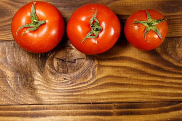 Verse rijpe tomaten op houten tafel. Bovenaanzicht, kopieer ruimte