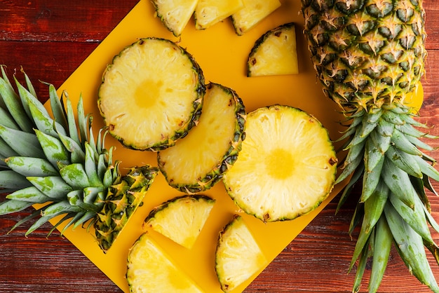 Verse rijpe tropische ananas die in plakken op gele rackside wordt gesneden die op een houten lijst liggen