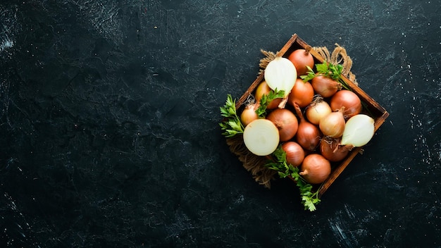 Verse rijpe uien in houten kist op zwarte achtergrond Bovenaanzicht Gratis exemplaarruimte