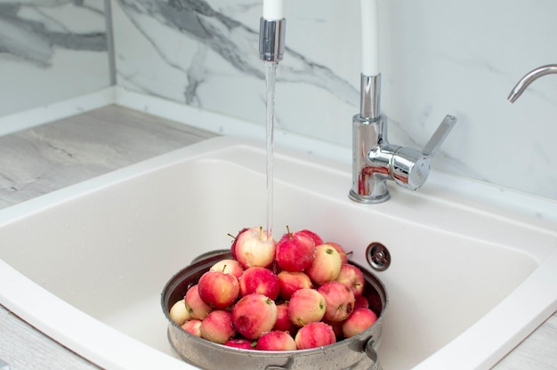 Verse rode appels in de gootsteen, close-up. Appels in een vergiet, gewassen onder stromend water.