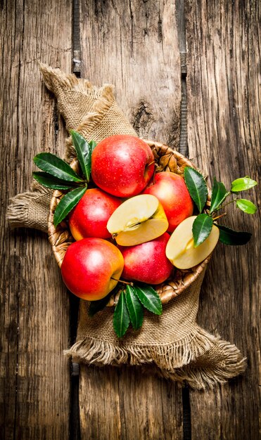 Verse rode appels met bladeren in de mand. Op een houten tafel. Bovenaanzicht