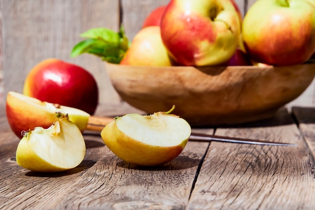 Foto verse rode appels met groene bladeren op een houten oude tafel.