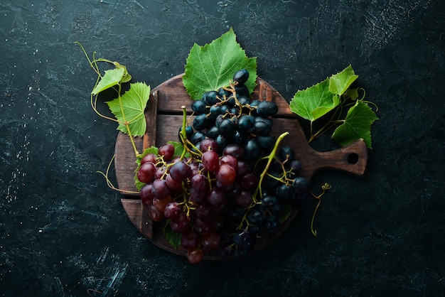 Verse rode druiven met bladeren op een zwarte stenen tafel. Bovenaanzicht. Vrije ruimte voor uw tekst.