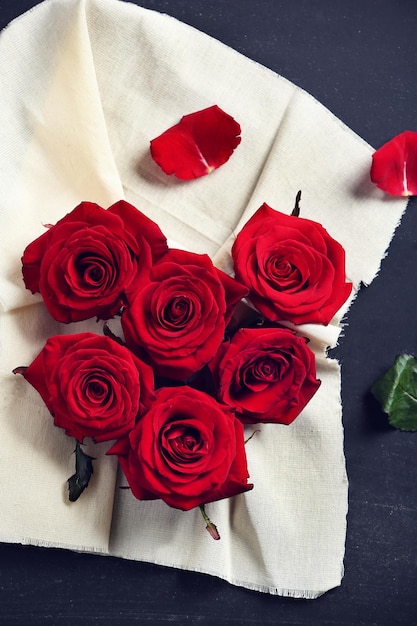 Verse rode rozenknoppen in de vorm van een hart met linnen stof op zwarte gestructureerde achtergrond
