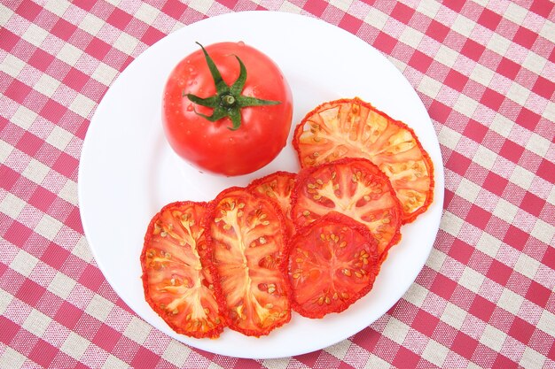 Verse rode tomaat en gedroogde tomatenplakken op een plaat. Vitamine plantaardig voedsel