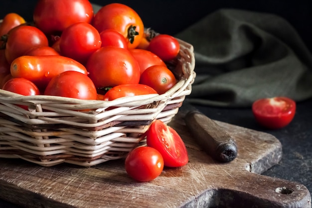 Verse rode tomaten in rieten mand op zwarte achtergrond.