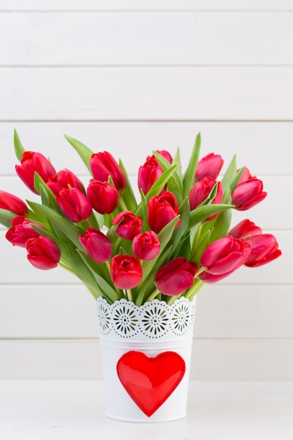 Verse rode tulp bloemen boeket op plank voor houten muur.