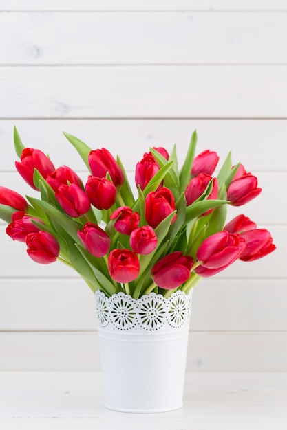 Verse rode tulp bloemen boeket op plank voor houten muur.