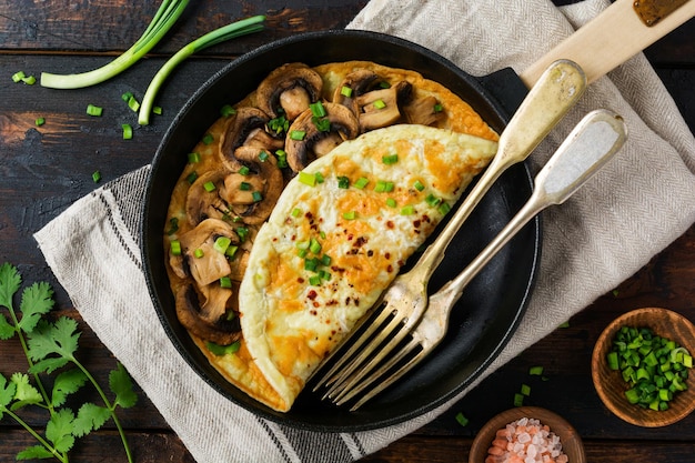Verse roerei-omelet of frittata met champignonsuien en verse kruiden op gietijzeren koekepan Bovenaanzicht met kopieerruimte