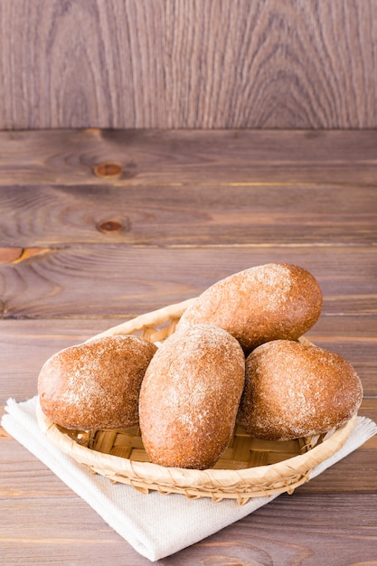 Verse roggebroodjes in een mand op een houten tafel