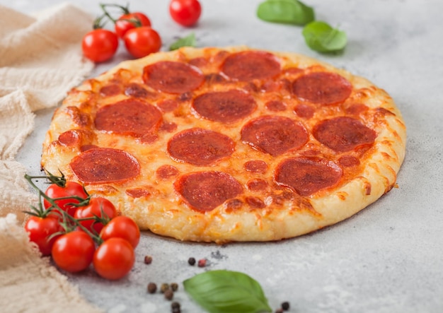 Verse ronde gebakken Italiaanse pizza Pepperoni met tomaten met basilicum op lichte keukentafelachtergrond Ruimte voor tekst