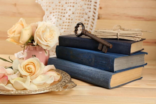 Verse rozen met oud boek, sleutel en letters op houten tafel achtergrond. vintage concept