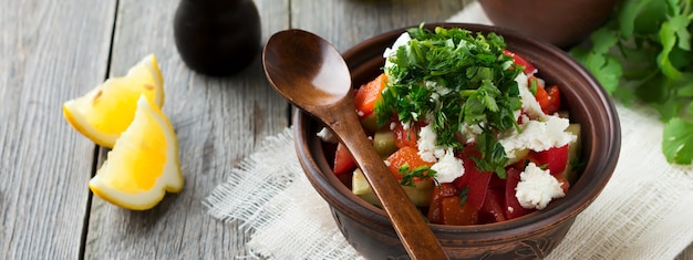 Verse Salade Shopska van gebakken paprika, tomaat, ui, komkommer, peterselie, dille en fetakaas in een keramische kom. Traditioneel Servisch eten. Selectieve aandacht.