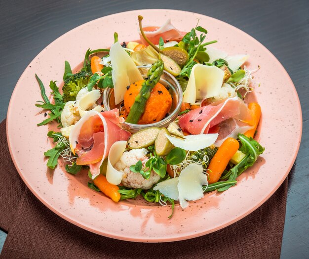 Verse salade van groenten, kaas en ham, op een gekleurde plaat