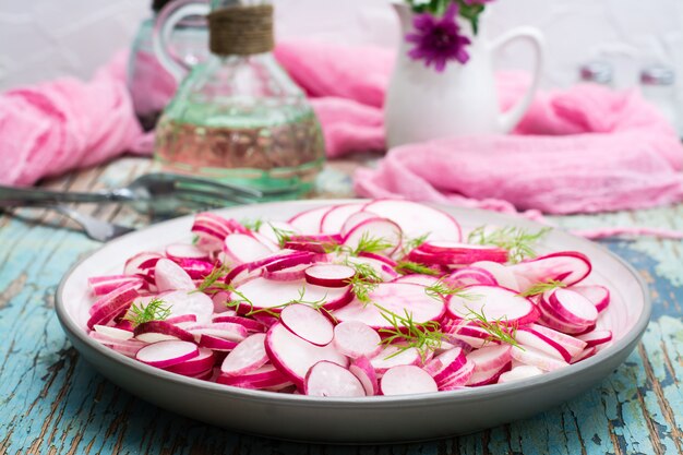 Verse salade van stukjes radijs en dille op een bord op een houten tafel. Klaar snack voor een dieet