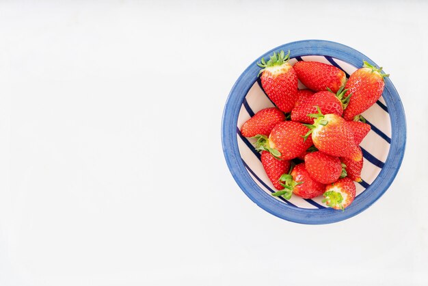 Verse, sappige aardbeien in ceramische die kom over wit bureau wordt geïsoleerd. Bovenaanzicht. Kopieer ruimte