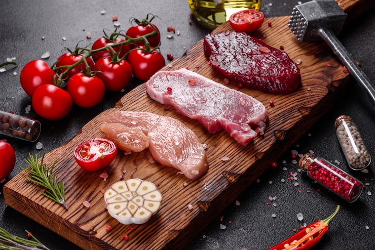 Foto verse, sappige biefstuk van rundvlees, varkensvlees en kip met groenten klaar om te koken. steaks van verschillende soorten vlees bereid om te koken