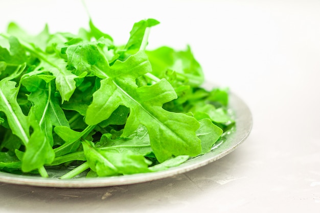 Verse, sappige bladeren van rucola op een lichte concrete achtergrond.