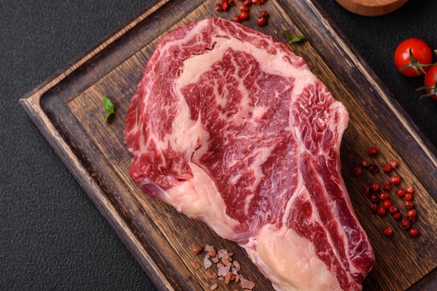Verse, sappige rauwe runderlendestuk steak met zout en kruiden op een donkere betonnen achtergrond
