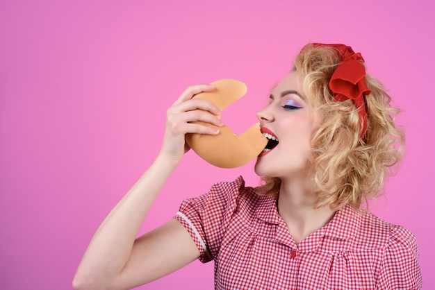 Verse sikkelbroodje bakkerijproducten gelukkige pin-up vrouw eet croissants vrouw in retro-stijl hold