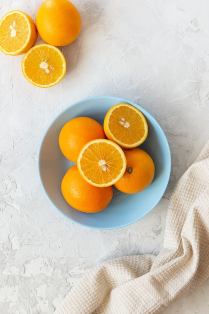 Verse sinaasappelen in een blauw bord op een grijze tafel