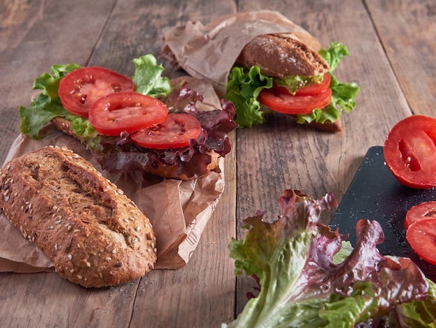 Verse sla en plakjes tomaat, stokbrood, geïsoleerd op een houten tafel