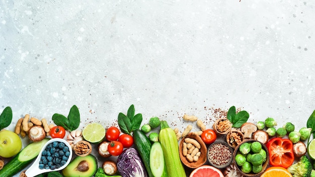 Verse smakelijke ingrediënten voor gezond koken of saladebereiding op een rustieke achtergrond bovenaanzicht banner Verse groenten, noten en fruit op een stenen achtergrond Bovenaanzicht Kopieer ruimte