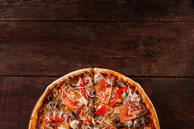 Verse smakelijke pizza geserveerd op rustieke houten tafel, plat gelegd. Traditionele Italiaanse keuken, pizzeria menu foto. Donkere achtergrond met vrije ruimte.