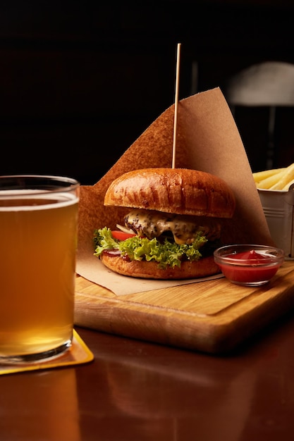 Verse smakelijke rundvleesburger met frietjes en bier op houten tafel in pub