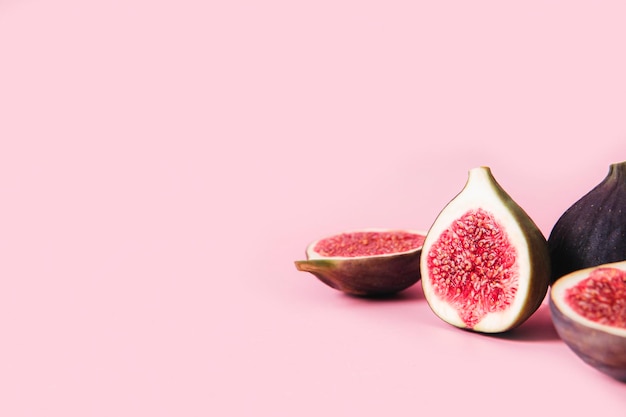 Verse smakelijke vijgenfruithelften met schaduw op roze achtergrond