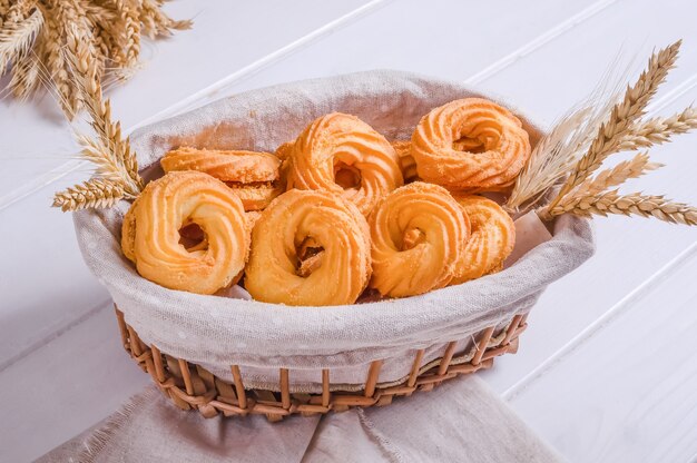 Verse smakelijke zandkoekkoekjes in een rieten mand op een witte houten achtergrond